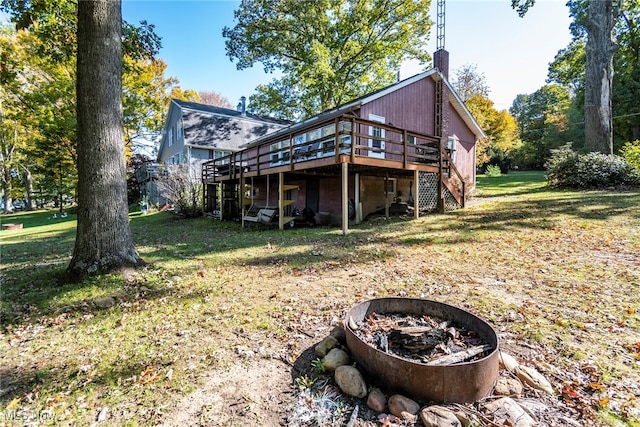 rear view of property with an outdoor fire pit, a yard, and a deck