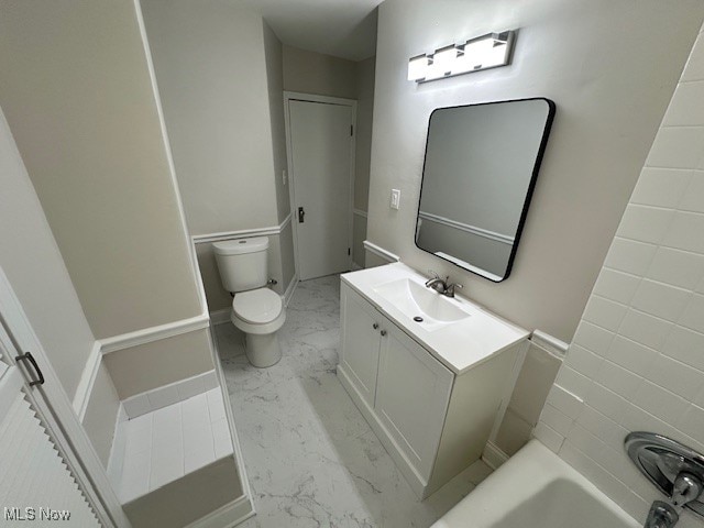 bathroom with vanity, toilet, and a washtub