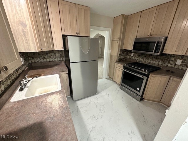 kitchen with stainless steel appliances, light brown cabinetry, backsplash, and sink