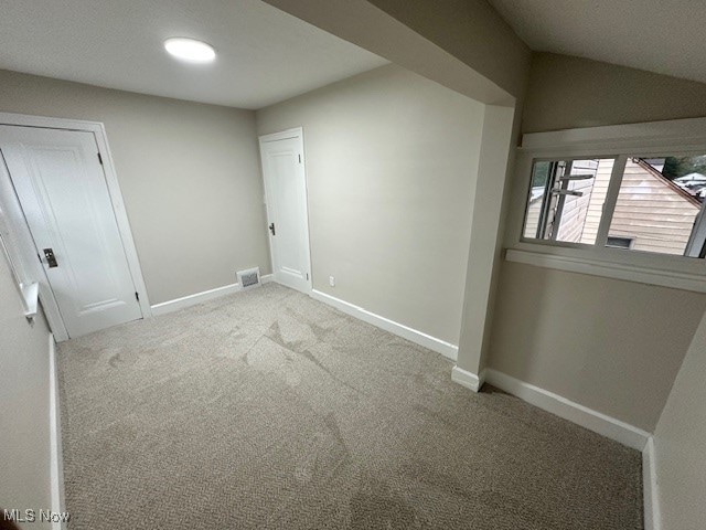 carpeted empty room with lofted ceiling