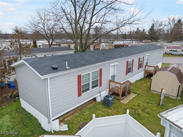 back of property featuring a lawn, a storage unit, and cooling unit