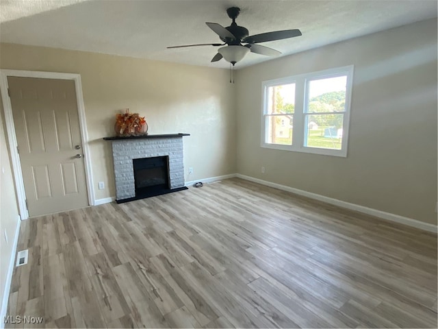 unfurnished living room with a fireplace, light hardwood / wood-style floors, and ceiling fan