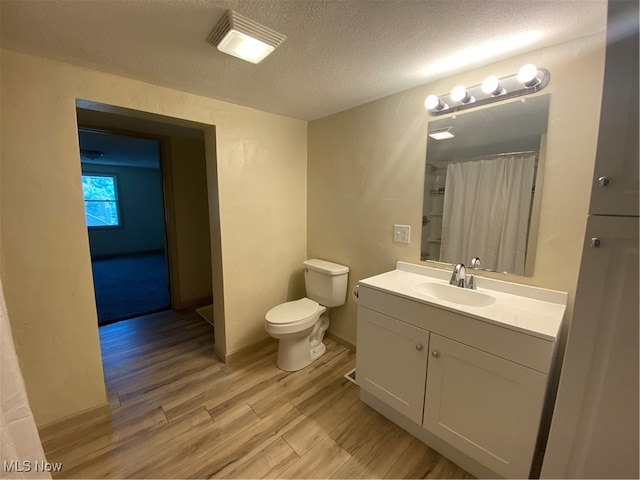 bathroom featuring toilet, vanity, hardwood / wood-style floors, and a textured ceiling