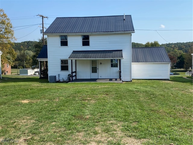 rear view of house with cooling unit and a lawn