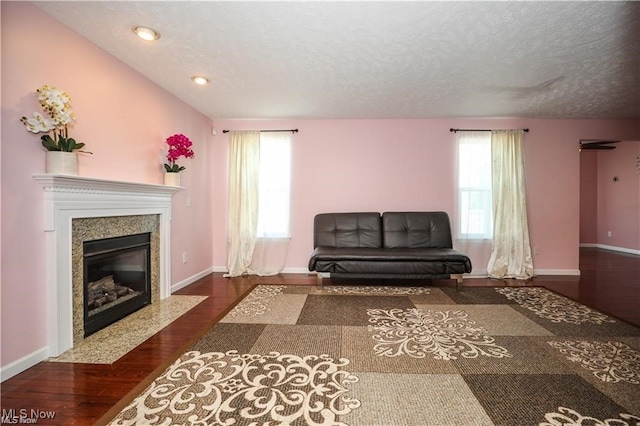 living room with dark wood-type flooring, a fireplace, and a textured ceiling