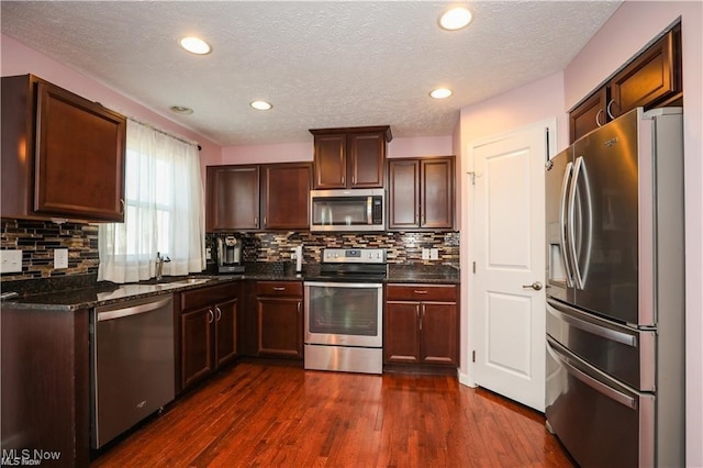 kitchen featuring a textured ceiling, stainless steel appliances, dark wood-type flooring, and tasteful backsplash