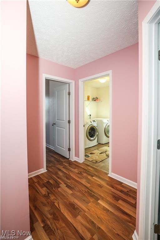 corridor featuring independent washer and dryer, dark hardwood / wood-style flooring, and a textured ceiling