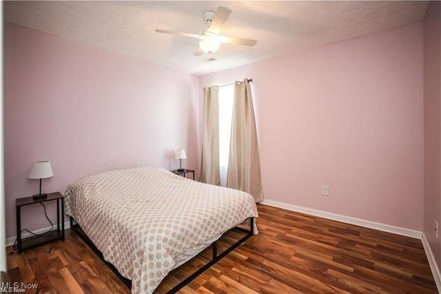 bedroom featuring dark wood-type flooring, a textured ceiling, and ceiling fan