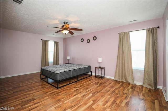 bedroom featuring ceiling fan, a textured ceiling, and hardwood / wood-style floors