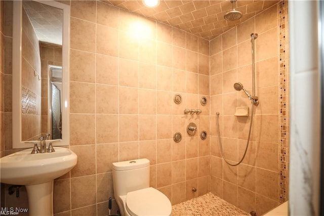 bathroom with toilet, tile walls, and a tile shower