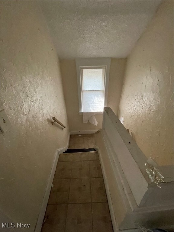 stairway featuring tile patterned flooring and a textured ceiling