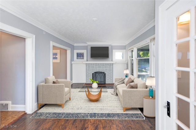 living room featuring crown molding, dark wood-type flooring, and a brick fireplace