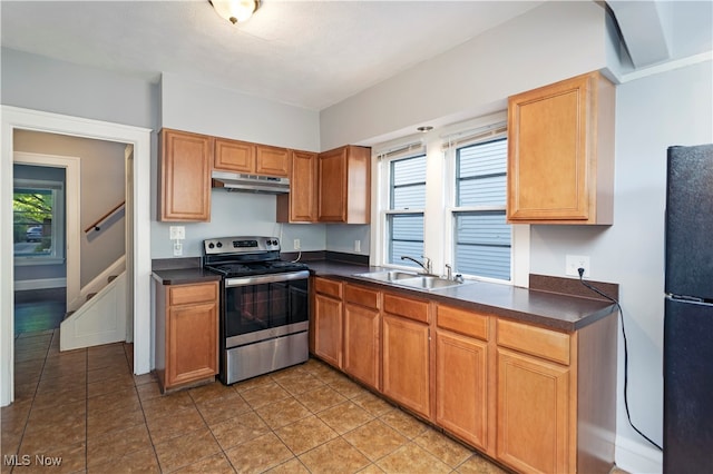 kitchen featuring stainless steel electric stove, black fridge, sink, and light tile patterned floors