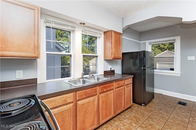 kitchen with black fridge, sink, electric range, and light tile patterned flooring