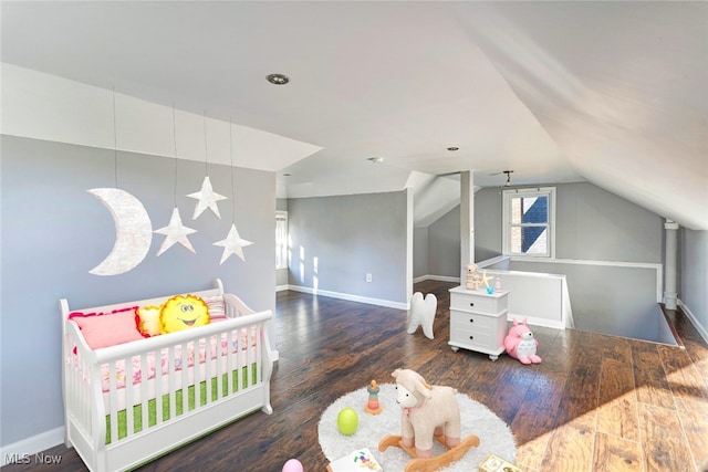 bedroom featuring a crib, lofted ceiling, and dark wood-type flooring