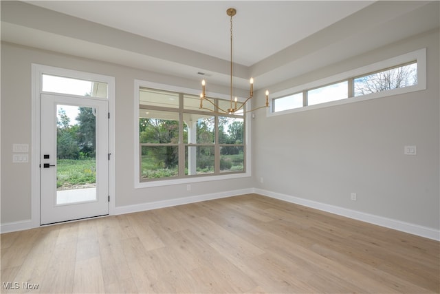 unfurnished dining area with light hardwood / wood-style floors and a notable chandelier