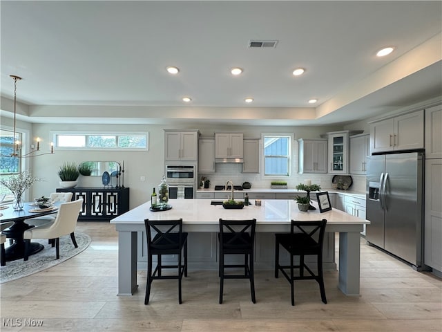 kitchen with a large island, stainless steel appliances, a breakfast bar, and light wood-type flooring