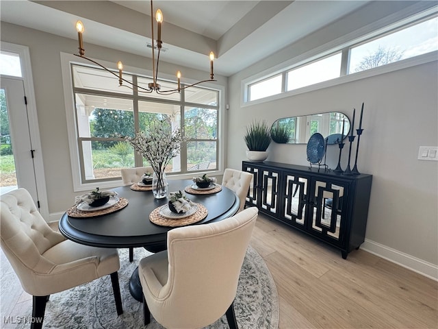 dining space with light hardwood / wood-style floors and a notable chandelier