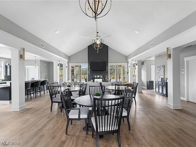 dining room featuring hardwood / wood-style floors, vaulted ceiling, a chandelier, and decorative columns