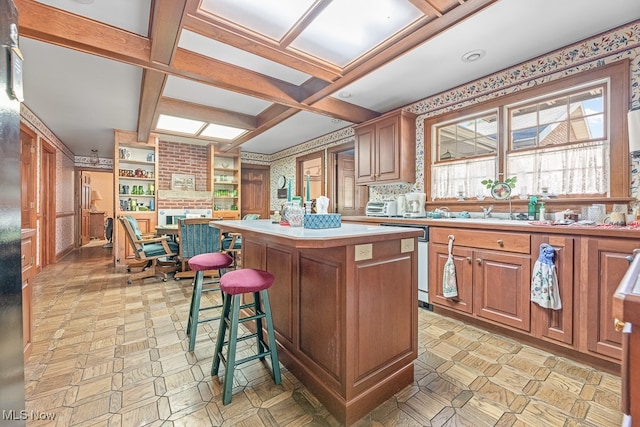 kitchen with a kitchen island, beamed ceiling, a breakfast bar, sink, and coffered ceiling