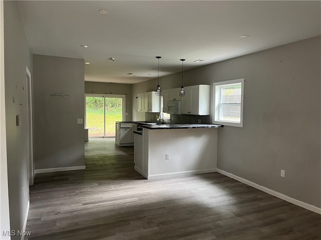 kitchen with kitchen peninsula, hanging light fixtures, white cabinets, and a healthy amount of sunlight