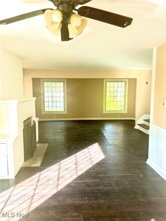 unfurnished living room with ceiling fan and dark wood-type flooring