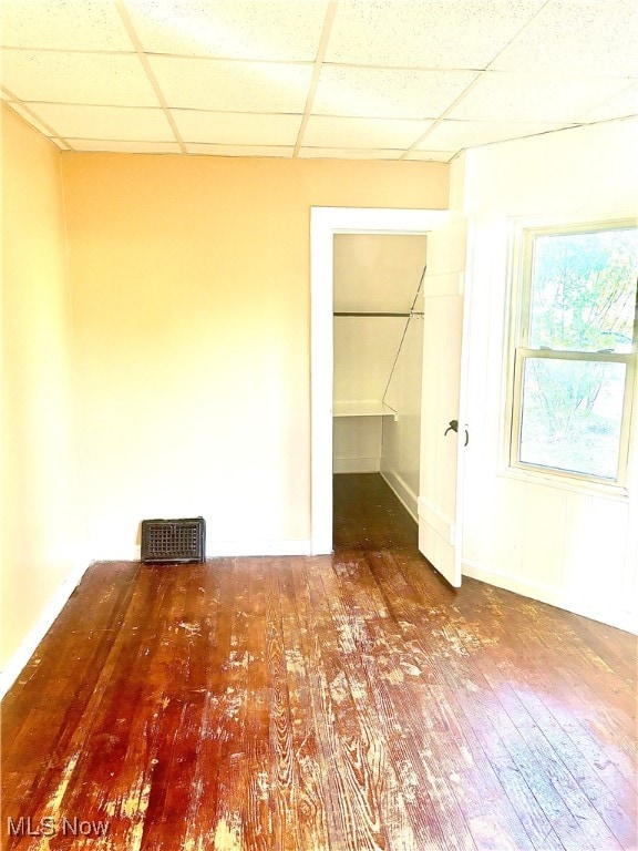 interior space with a drop ceiling and hardwood / wood-style flooring