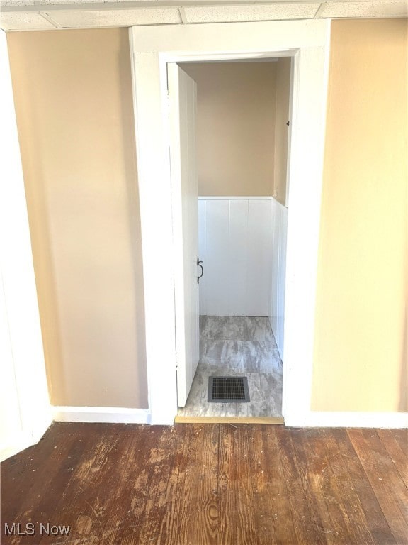 corridor featuring a drop ceiling and wood-type flooring