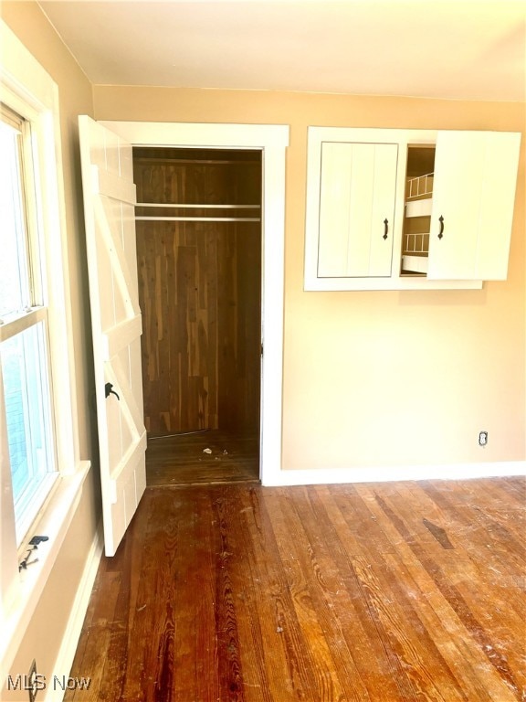 unfurnished bedroom with dark wood-type flooring and a closet