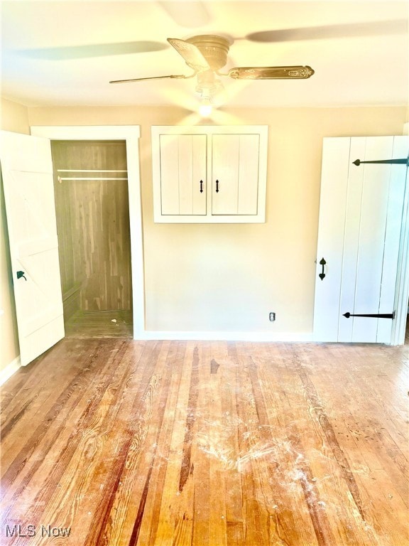 unfurnished bedroom with ceiling fan, light wood-type flooring, and a closet