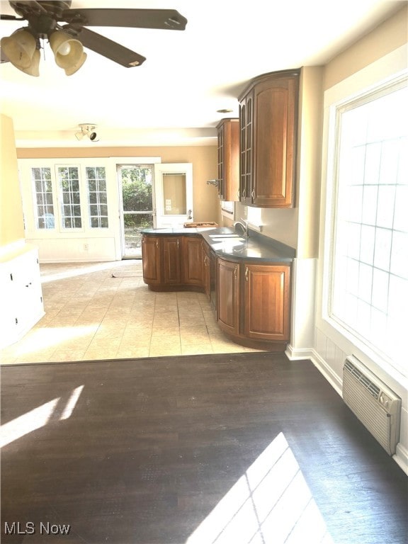 kitchen featuring light wood-type flooring, a wall unit AC, ceiling fan, and sink