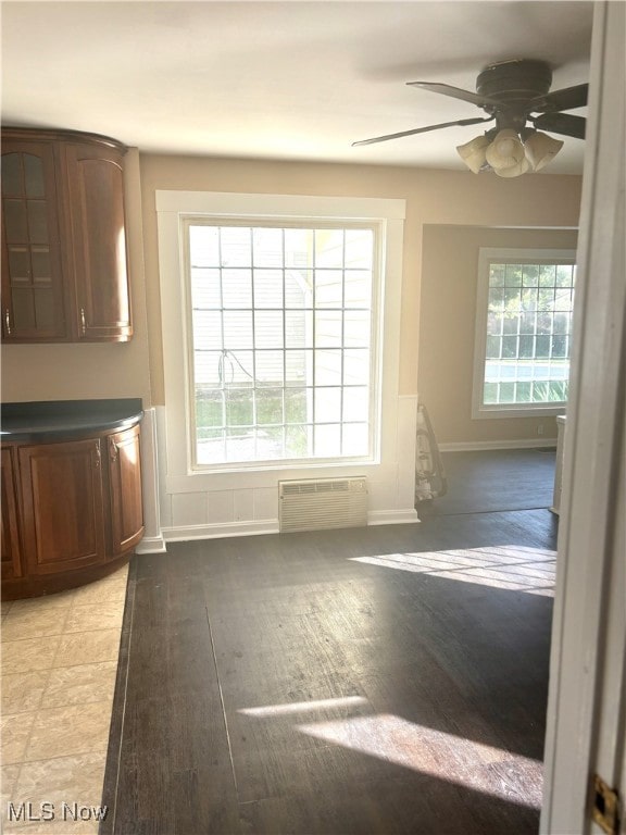 interior space featuring ceiling fan, a wall mounted AC, light hardwood / wood-style flooring, and a healthy amount of sunlight