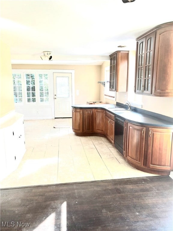 kitchen with light tile patterned floors, black dishwasher, and sink