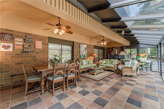 dining room featuring brick wall, ceiling fan, and a skylight