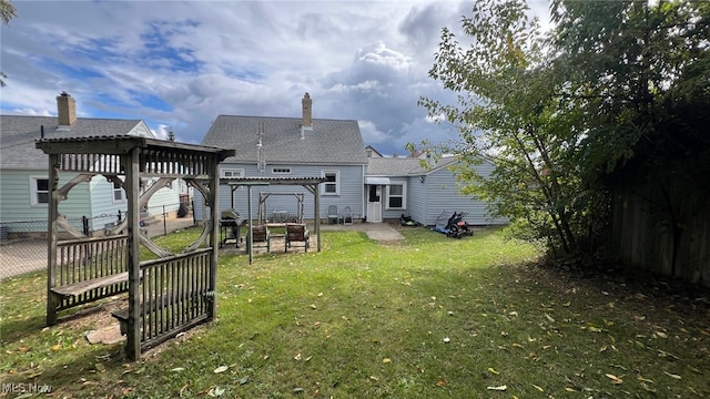 rear view of property featuring a yard and a pergola