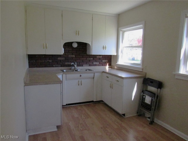 kitchen featuring light wood-type flooring, sink, tasteful backsplash, and white cabinetry