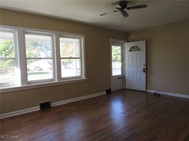 unfurnished room featuring dark wood-type flooring, a wealth of natural light, and ceiling fan