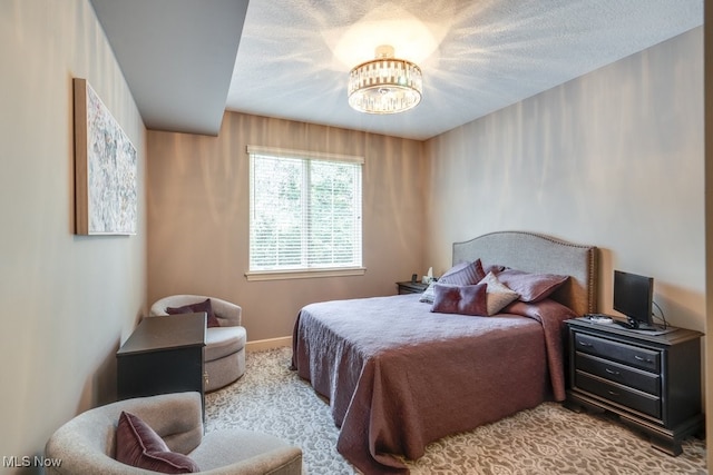 bedroom featuring an inviting chandelier, a textured ceiling, and light carpet