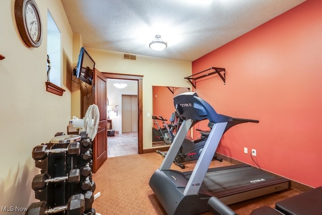 exercise room with carpet and a textured ceiling