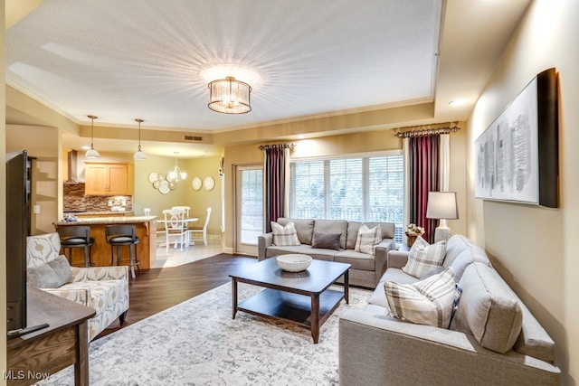 living room featuring ornamental molding, a notable chandelier, and dark wood-type flooring