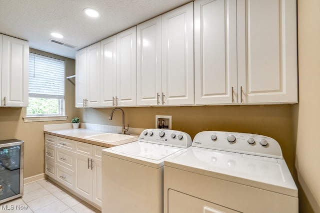 laundry room featuring cabinets, beverage cooler, washer and dryer, sink, and a textured ceiling