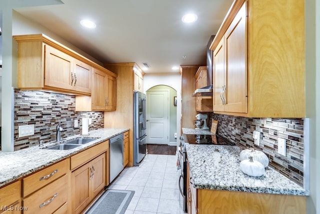 kitchen featuring backsplash, appliances with stainless steel finishes, sink, and light stone counters