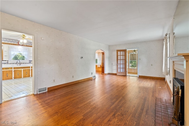 unfurnished living room with ceiling fan, hardwood / wood-style flooring, and a healthy amount of sunlight