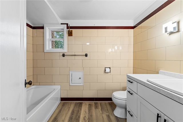 bathroom featuring wood-type flooring, tile walls, vanity, and toilet