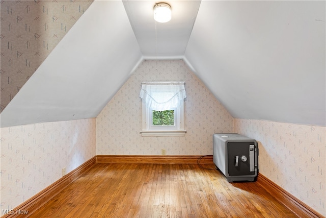 additional living space featuring light wood-type flooring and vaulted ceiling