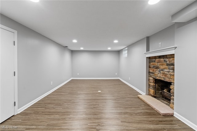 unfurnished living room featuring a stone fireplace and hardwood / wood-style floors