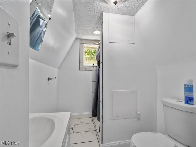 bathroom with a textured ceiling, vaulted ceiling, vanity, and toilet