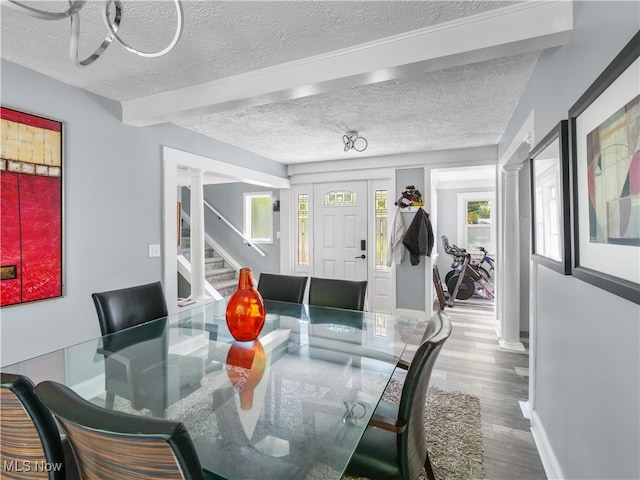 dining room with decorative columns, beamed ceiling, hardwood / wood-style floors, and a textured ceiling