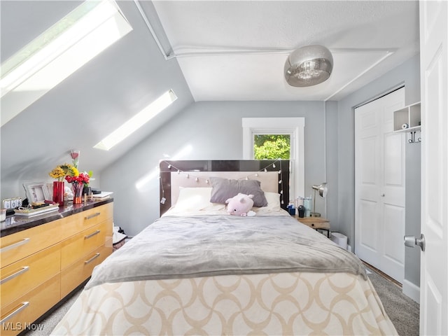 bedroom featuring vaulted ceiling with skylight, a closet, and carpet flooring