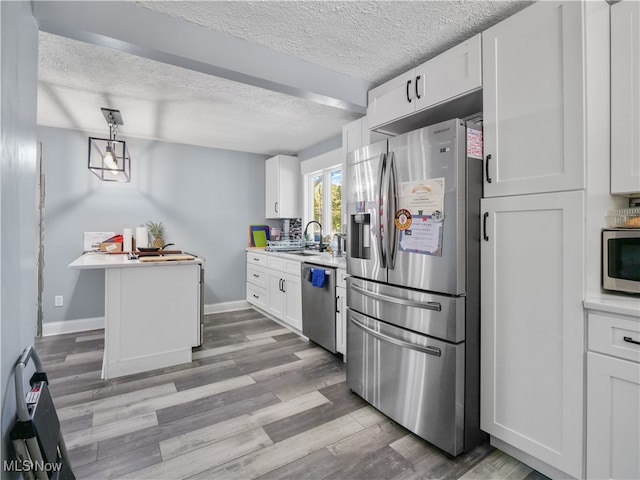 kitchen with stainless steel appliances, hanging light fixtures, light hardwood / wood-style floors, and white cabinets